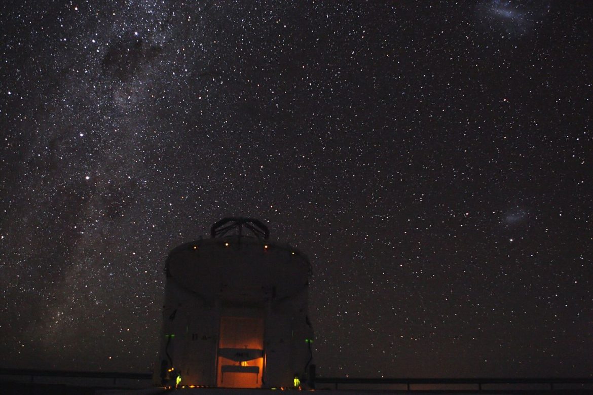 A telescope silhouetted against a starry night sky